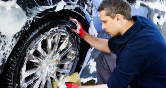 Man worker washing car's alloy wheels on a car wash