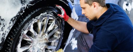 Man worker washing car's alloy wheels on a car wash