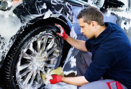 Man worker washing car's alloy wheels on a car wash